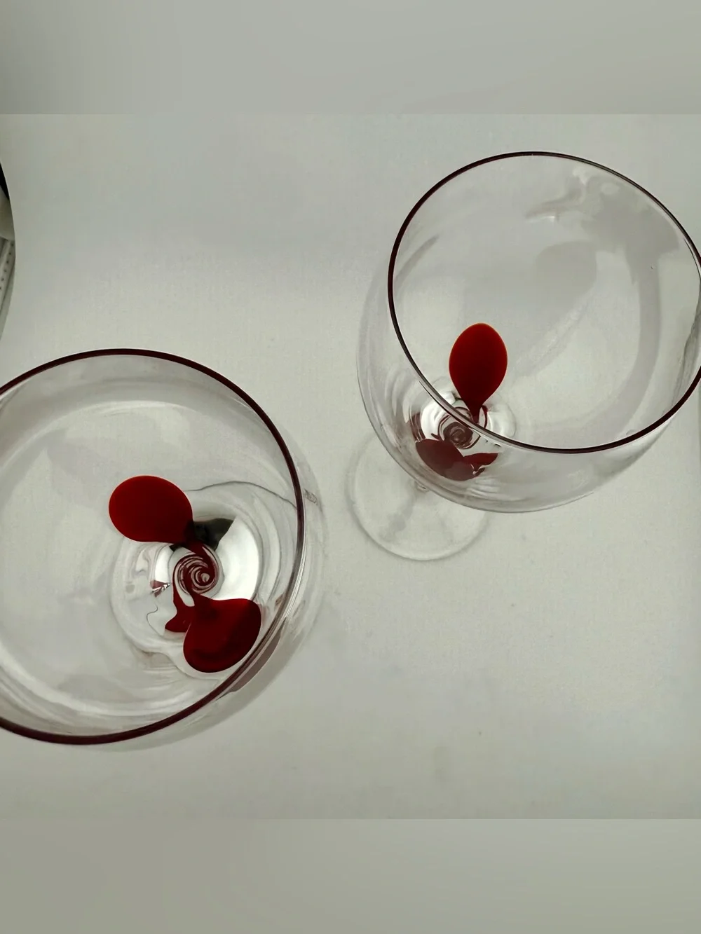 2 Pier 1, red ribbon swirl stem wine glasses, w/ a red swirl design on the stem.